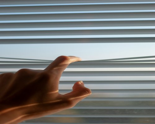Person adjusting blinds for natural light